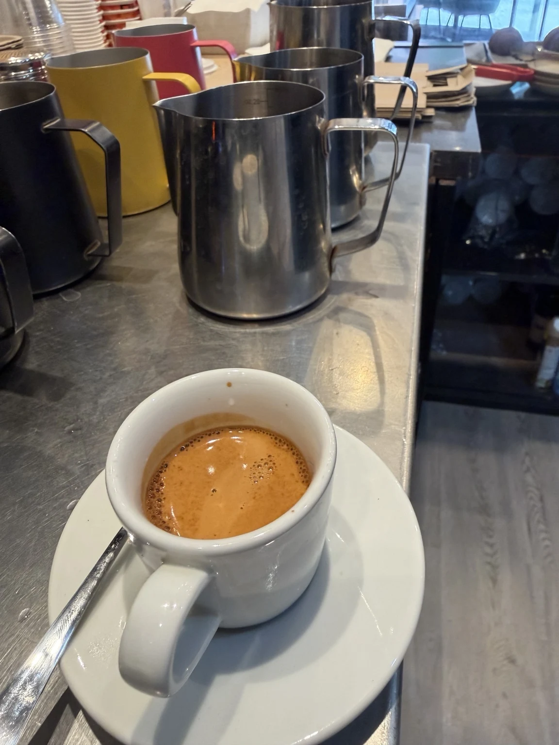 Fresh espresso with milk pitchers on a café worktop