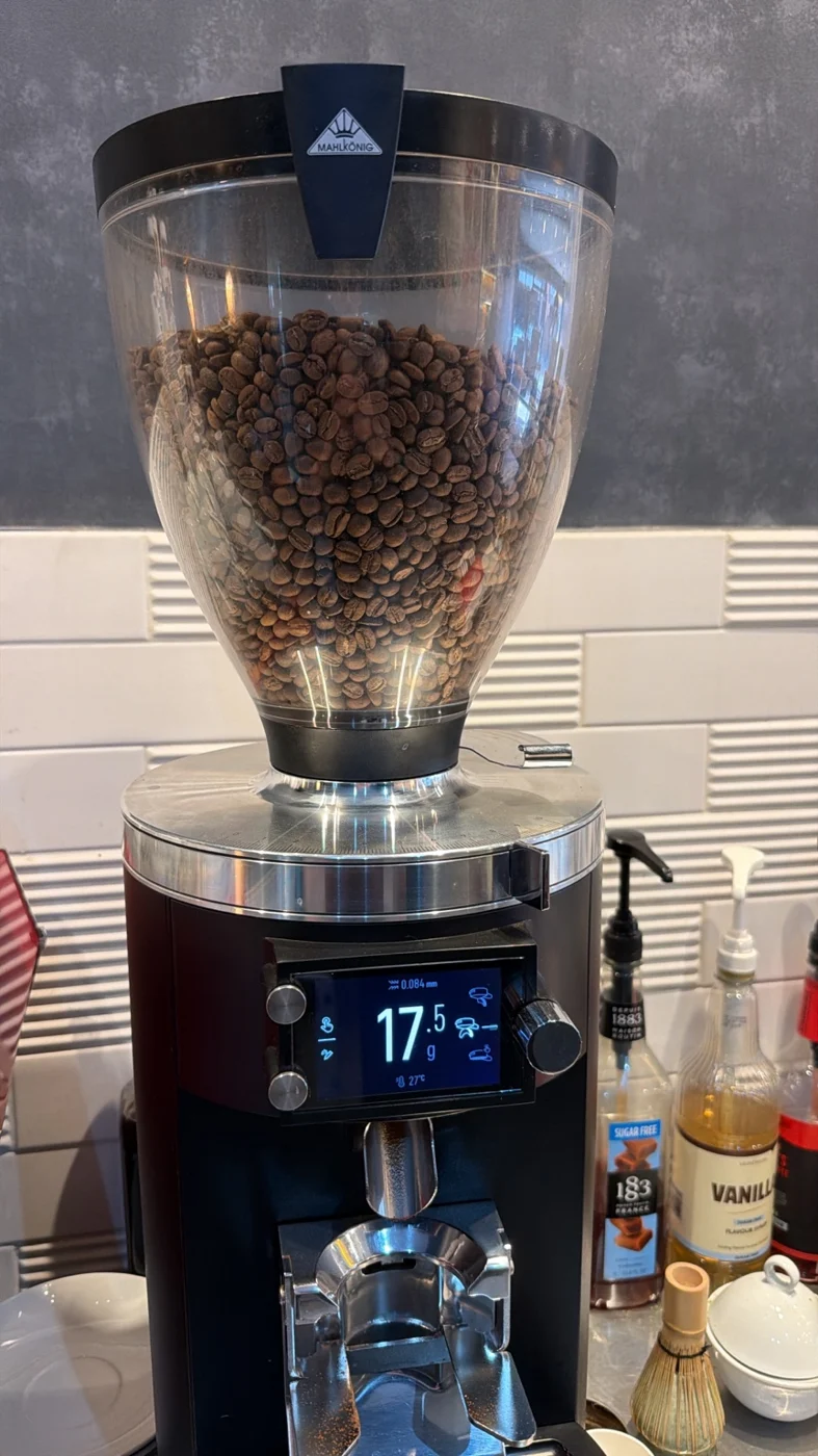 Commercial espresso grinder with coffee beans and a portafilter