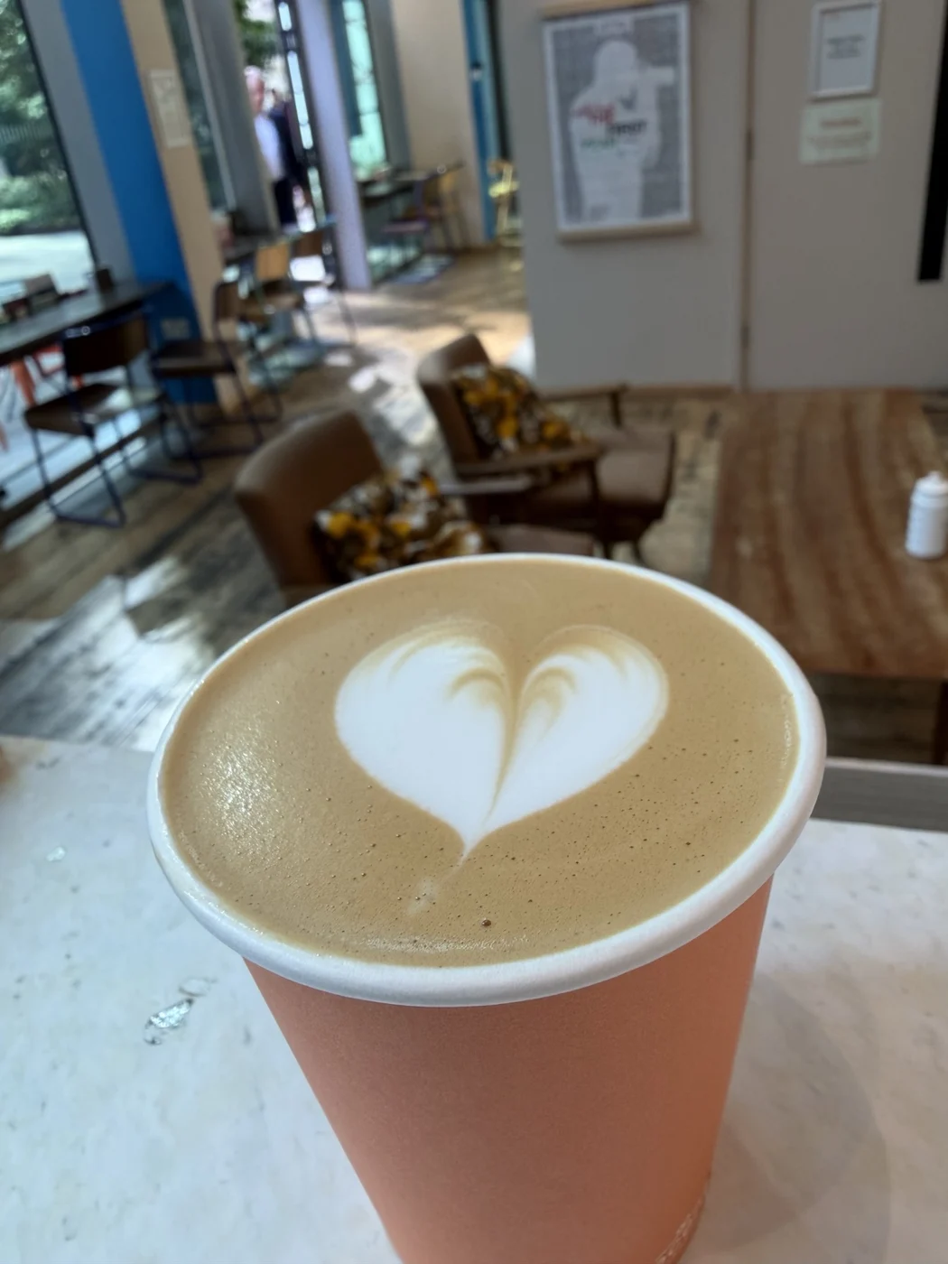 Heart latte art in an orange takeaway cup