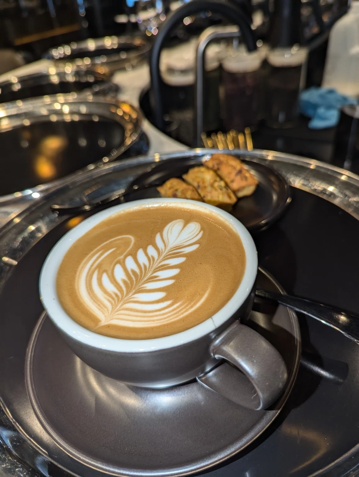 Detailed rosetta latte art in a dark ceramic cup